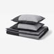 Grey BRUNKRISSLA bedding set with pillows, folded neatly.