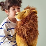 Young girl hugs large stuffed lion toy, both providing comfort and companionship.