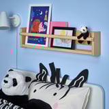 Kids room with blue wall, zebra pillow bed, shelf with drawings, small panda toy.