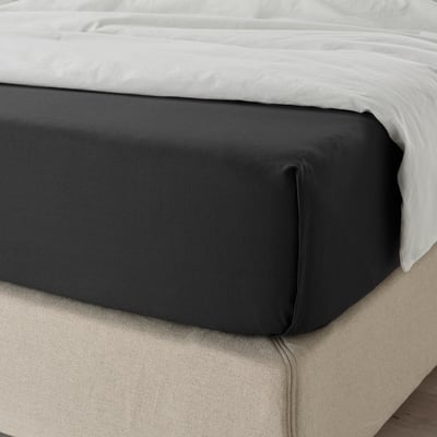A neatly made bed with black cotton fitted sheet on a white mattress, showcasing its softness and secure fit.