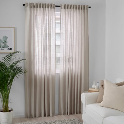 Minimalist room with light beige DYTÅG linen curtains, white couch, and large plant.