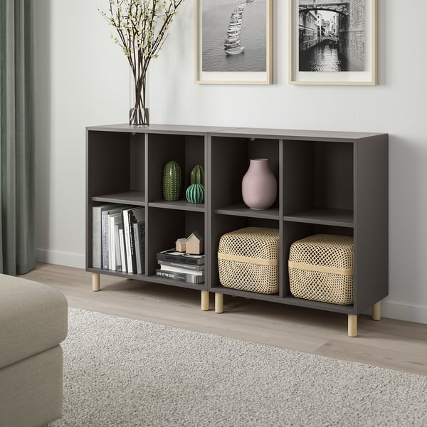 A modern living room with an EKET black storage unit, books, decor, and a beige sofa.