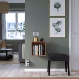 Modern living room with green wall, bookshelf, plant art, bench, large window.