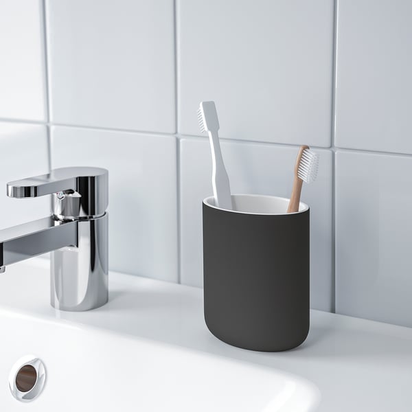 Modern bathroom with chrome faucet, gray toothbrush holder, and two toothbrushes on white countertop. EKOLN.