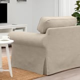 Beige EKTORP armchair with soft, reversible cushions in minimalist living room. Coffee on side table beside.