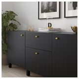 Modern black cabinet with gold knobs, displaying decorative items and books.