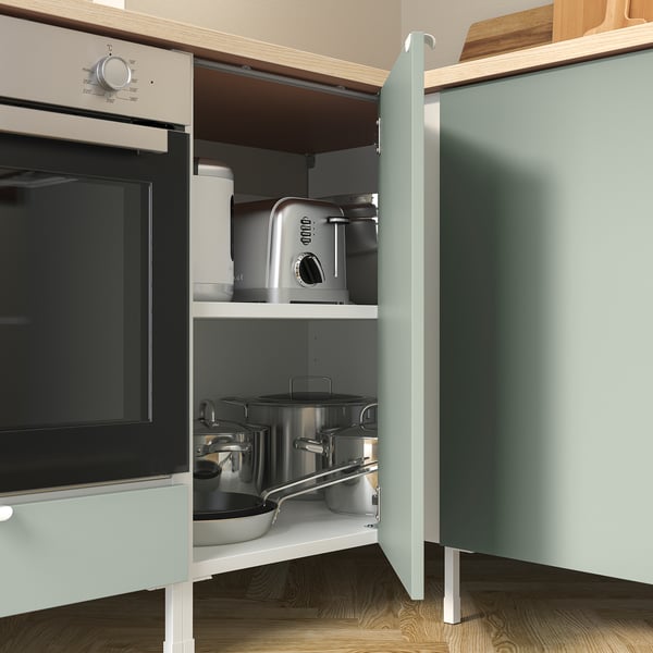 This image shows a kitchen cabinet with an oven inside. The cabinet has shelves holding pots and pans. The drawer is labeled ENHET.