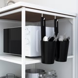 White microwave on open shelf with black containers holding utensils beneath, organized kitchen storage.