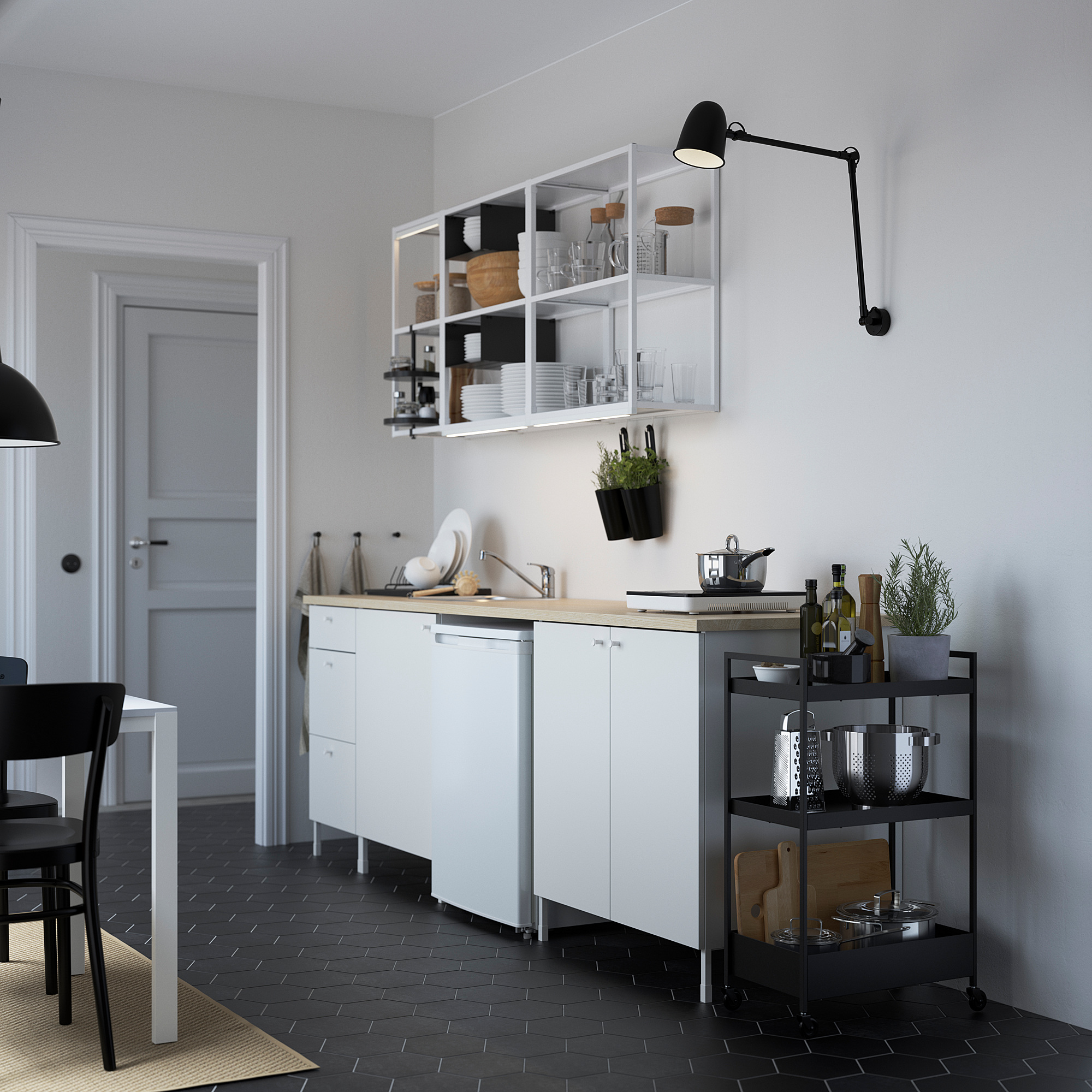 Modern kitchen with white ENHET cabinets, wood countertop, open shelves, black rolling cart, and wall lamp.
