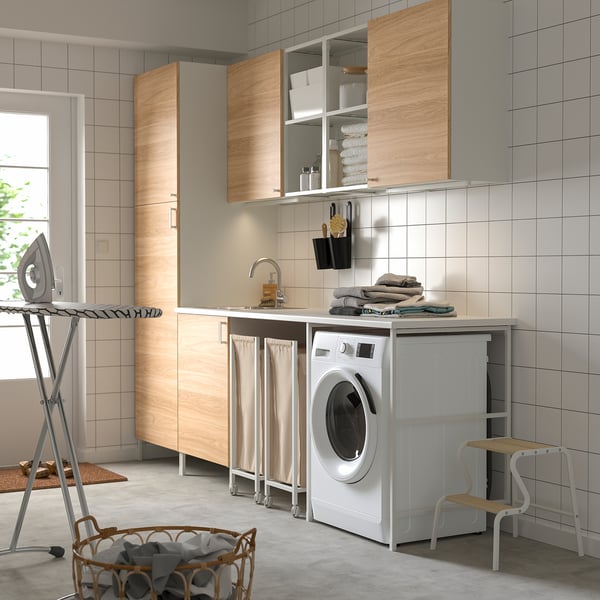 Modern laundry room with wooden white elements, ENHET cabinets, washing machine, towel display.