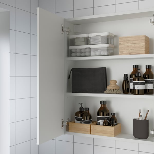 Open bathroom cabinet with mirrored door, showing shelves with organized toiletries and containers.