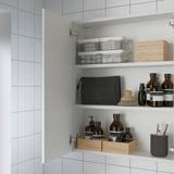 Open bathroom cabinet with mirrored door, showing shelves with organized toiletries and containers.