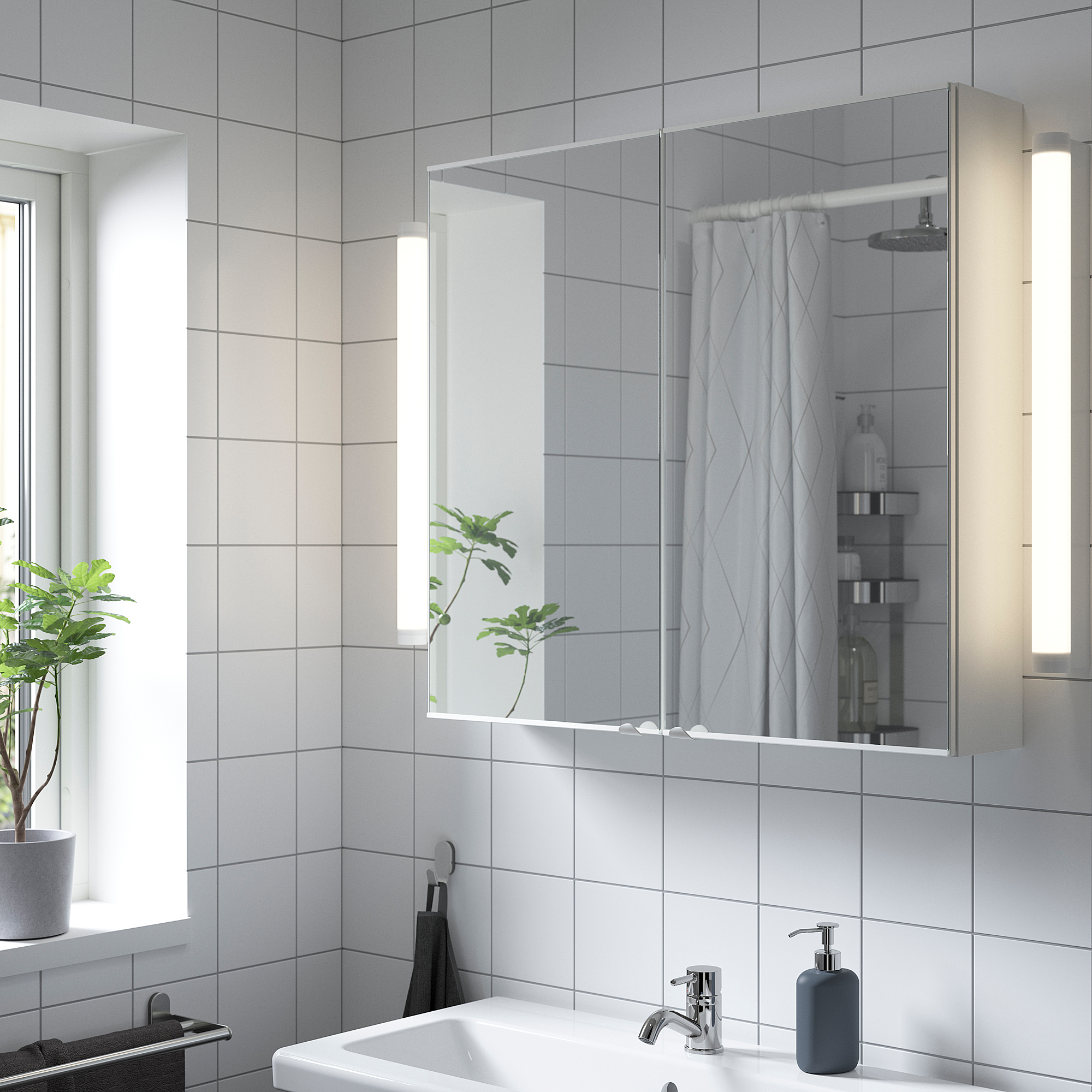 ENHET mirror cabinet over bathroom sink, sleek & bright, compact storage, integrated lights, plant beside.