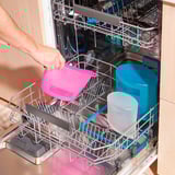 A person places colorful, reusable FILFISK bags in a dishwasher, highlighting their dishwasher-safe feature.