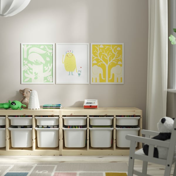 Three colorful framed pictures above wooden shelf with toy-filled bins.