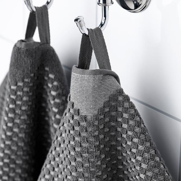 Two towels hang neatly on chrome hooks. The front towel a pattern with fringe, indicating its decorative and absorbent qualities.
