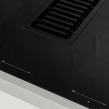 Black modern induction hob with integrated vent, glossy surface, digital controls visible.