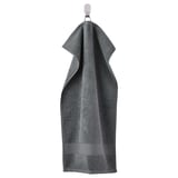 A grey FREDRIKSJÖN towel, thick and plush, hanging. Its made of 100% cotton with a woven border detail.