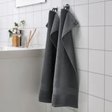 Dark grey FREDRIKSJÖN towels hung neatly, larger than toiletries.