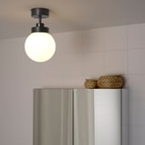 Modern kitchen with frosted light fixture, stainless fridge, pastel tiles.