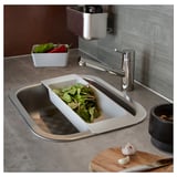 Modern kitchen sink in stainless steel with gray countertop, chrome faucet, and various utensils.