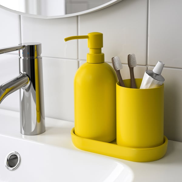 Bright yellow bathroom accessories: soap dispenser, toothbrush holder, and tray on a white sink.