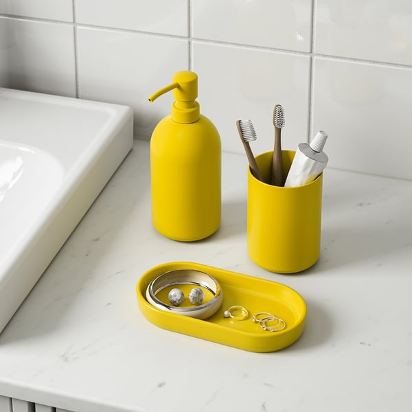Yellow bathroom set on marble counter: soap dispenser, toothbrush holder, and tray with jewelry.