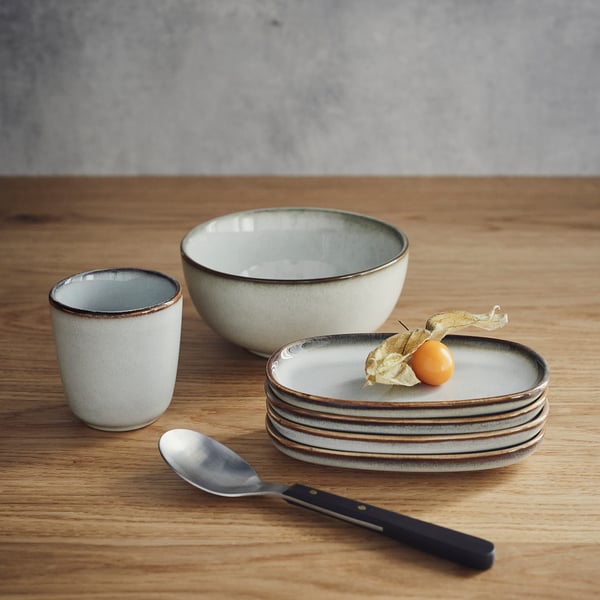 GLADELIG set: small cup, medium bowl, stacked plates, spoon, fruit. Sandy glaze, diverse sizes.