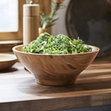 Wooden bowl with salad on table.