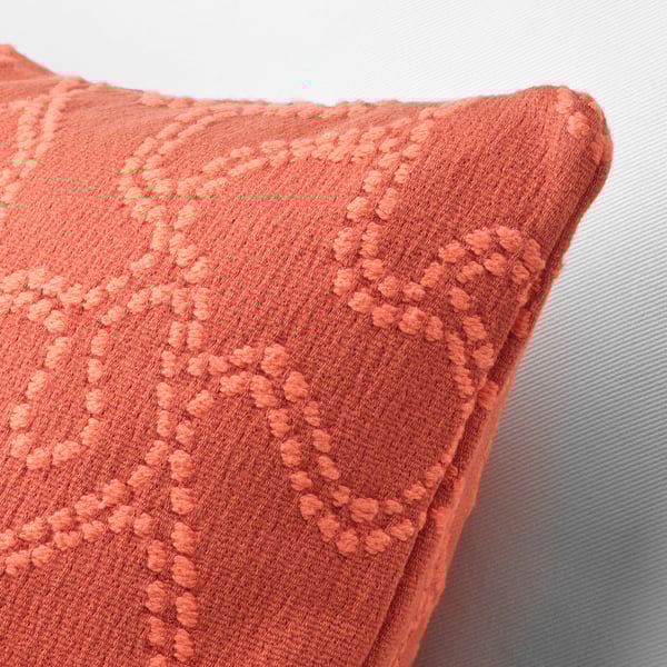 A close-up of a soft, textured orange cushion cover with intricate, elevated patterns.