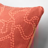 A close-up of a soft, textured orange cushion cover with intricate, elevated patterns.