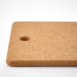Natural cork trivet with a small hole, rectangular shape, laid flat on a white surface.