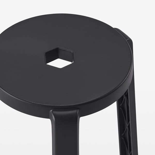 Black round stool with three legs, one with a small hole, modern design, sturdy and stackable.
