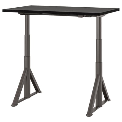 An IDÅSEN adjustable desk in black with a rectangular top and triangle legs. Its height-adjustable and cable management.