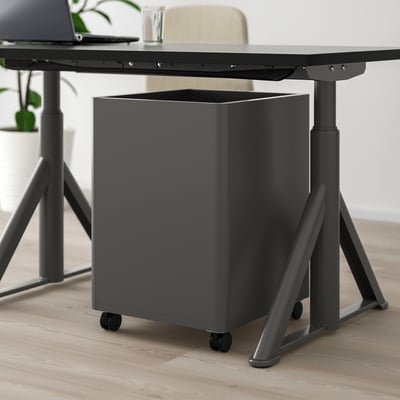 Black under-desk drawer unit on wheels, part of a modern office setup.