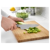 Chopping celery on a wooden cutting board with a stainless steel chefs knife.