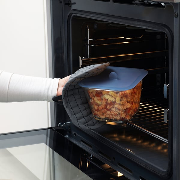 Person puts glass container with vacuum lid into oven.