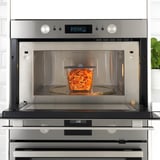 Stainless steel microwave with glass container, showing vacuum lid for food freshness.