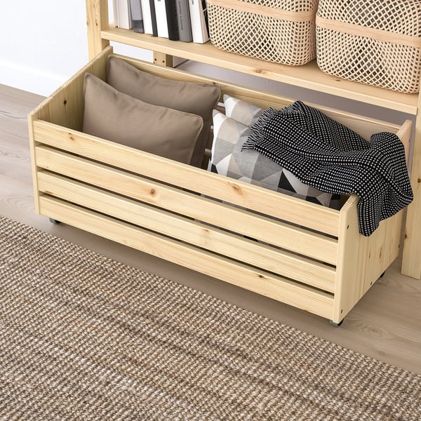 Wooden storage bench with cushions and throws, part of IVAR series, in minimalist room.