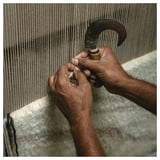 Hands crafting JULGRANSGRÄS rug, weaving wool into striped, sandy texture.