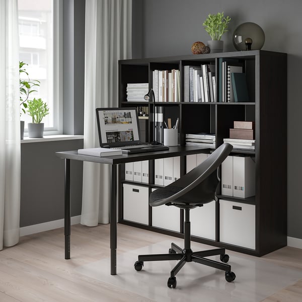 Home office with KALLAX shelf, desk, chair, laptop, books, plants, and window.