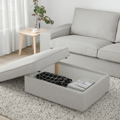 Light grey KIVIK footstool with ottoman opened, revealing storage space filled with magazines and a patterned box.