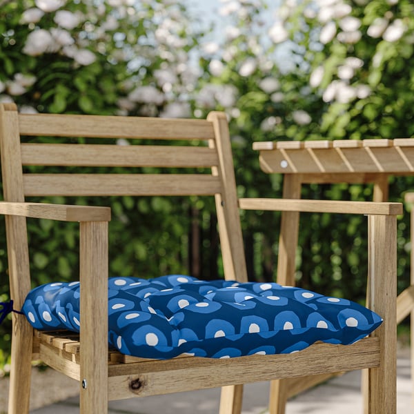 Wooden park bench with blue and white patterned round cushion.