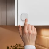 Hand pressing KNYCKLAN button to control dishwasher water supply.