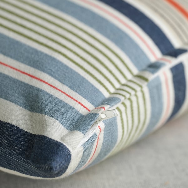 Close-up of striped cushion cover featuring a subtle, textured fabric with a hidden zipper.