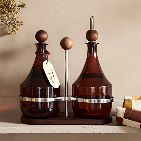 KRÖSAMOS bottle stoppers: set of 3 brown wooden tops with stainless steel center, designed for bottled beverages, sitting on rustic wooden stand.