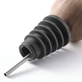 Close-up of a robust drip stopper made of silicone, solid walnut, and stainless steel. Fits various bottles, ensuring no spills.