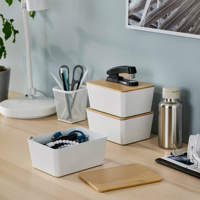 Organized workspace with white KUGGIS box, bamboo lid, pen holder, storage boxes, metal water bottle, and wooden mousepad.