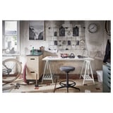 Industrial-themed workspace with white LAGKAPTEN table, black stool, and various decorative items.