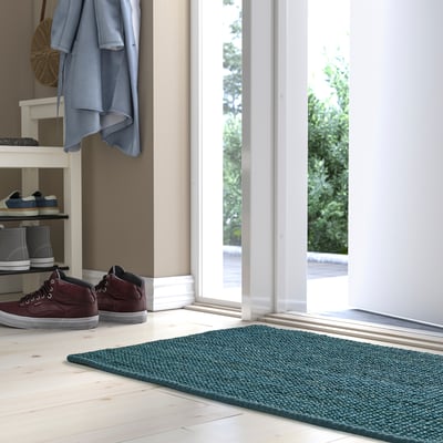 Dark blue LANDBANA jute mat near entrance, fits under shoe rack.